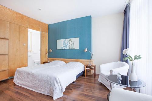 a bedroom with a white bed and a blue wall at Hotel Gevers in Scheveningen