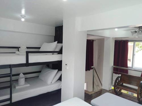 a room with three bunk beds with a bench and a window at NVH3 Coron Palawan in Coron