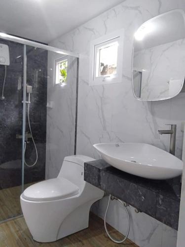 a bathroom with a toilet and a sink and a shower at NVH3 Coron Palawan in Coron