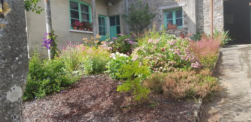 a garden with flowers in front of a house at Gîte Ker André à 15 minutes du Puy du Fou in Pouzauges