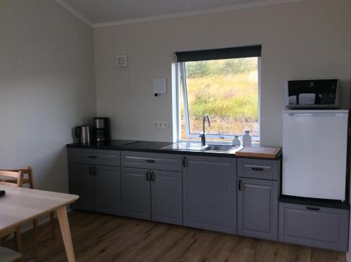 a kitchen with a sink and a refrigerator and a window at Hvammstangi Hill Homes in Hvammstangi