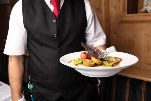 a man is holding a plate of food at Hotel Rotlechhof in Berwang