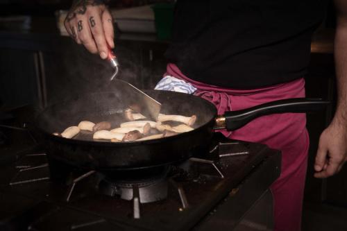a person cooking food in a pan on a stove at Hotel Rotlechhof in Berwang