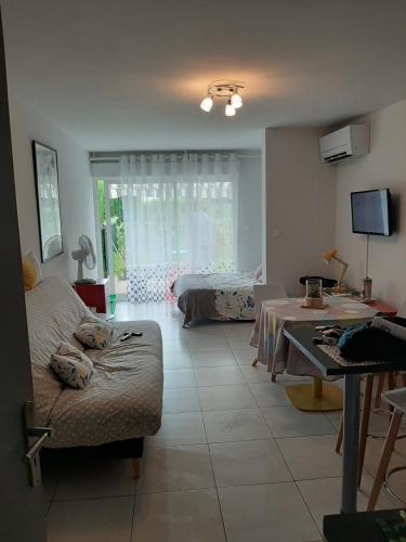 een woonkamer met een bank en een tafel bij Studio avec jardinet clim parking in Gruissan