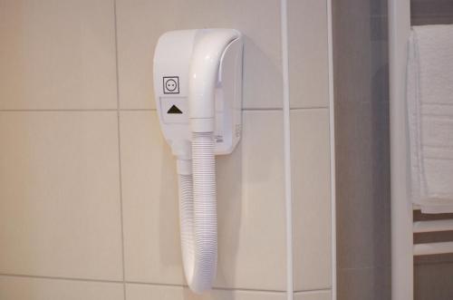 a white hairdryer on a wall in a bathroom at Hôtel Héliot, Cosy Places by Charme & Caractère in Toulouse