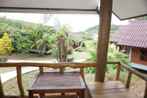 a wooden bench on a porch with a view of a yard at Mookanda bungalow in Ko Yao Noi