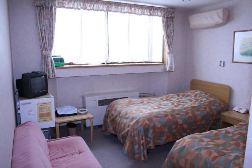 a hotel room with two beds and a tv at Akakura Wakui Hotel in Myoko