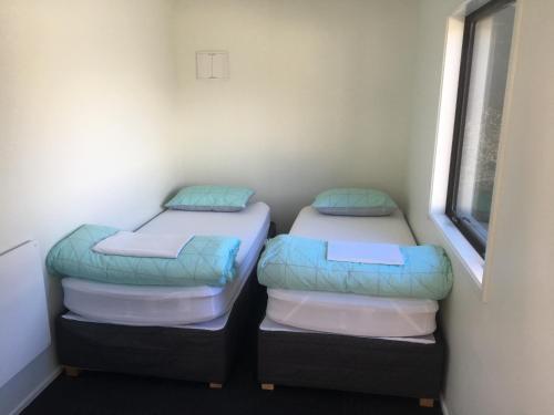 two twin beds in a room with a window at Qbox in Queenstown