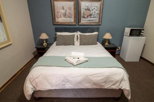 a bedroom with a bed with two towels on it at Lala Dene Lodge in Bloemfontein