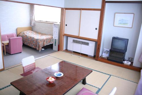 a room with a table and a bed and a television at Akakura Wakui Hotel in Myoko