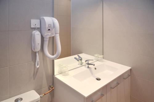 a bathroom with a sink and a phone on the wall at Hôtel Héliot, Cosy Places by Charme & Caractère in Toulouse