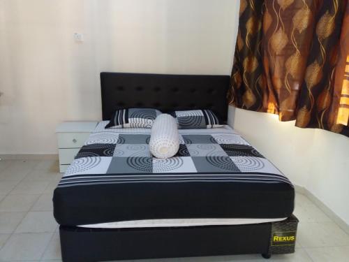 a bedroom with a bed with a black and white comforter at Seri Baqti Homestay in Tanah Merah
