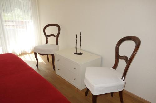 a bedroom with two chairs and a dresser and a bed at Exclusive Central Apartment in Basel