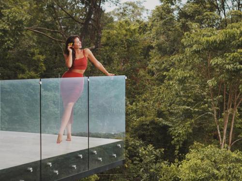 a woman talking on a cell phone while standing on a glass wall at Rancho Pacifico - Boutique Hotel for Adults in Uvita