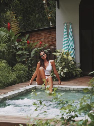 a woman in a bikini sitting next to a swimming pool at Rancho Pacifico - Boutique Hotel for Adults in Uvita
