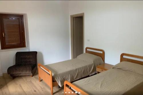 Pratella的住宿－Vista sul Lete，客房设有两张床、一把椅子和窗户。