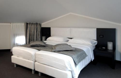 a bedroom with a white bed with white sheets and pillows at Hotel Villa Pannonia in Venice-Lido