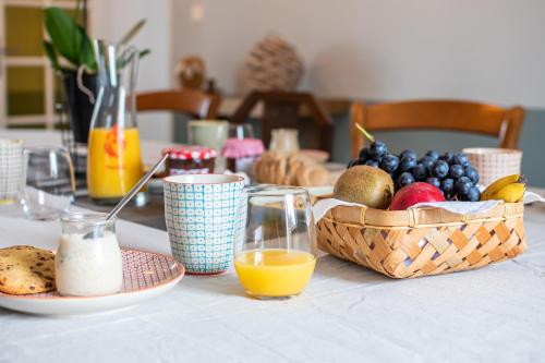 Una mesa con un bol de fruta y una cesta de zumo. en Le DOMAINE DES ECOLIERS B&B, en Montaigu-Vendée