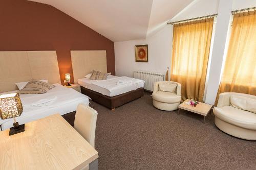 ビイェロ・ポリェにあるHotel Dominusのベッド2台、テーブルと椅子が備わるホテルルームです。