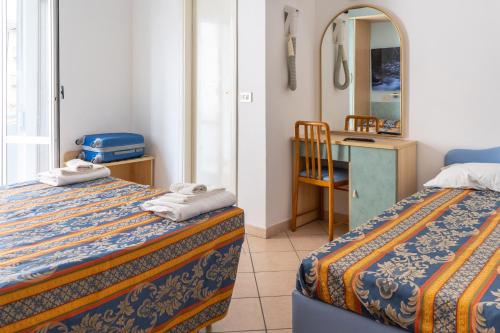 a hotel room with two beds and a mirror at Hotel Tiglio in Rimini
