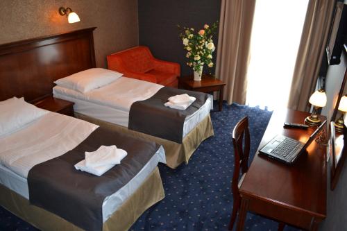 a hotel room with two beds and a laptop on a table at Borowinowy Zdrój Hotel Wellness Spa & Conference in Supraśl