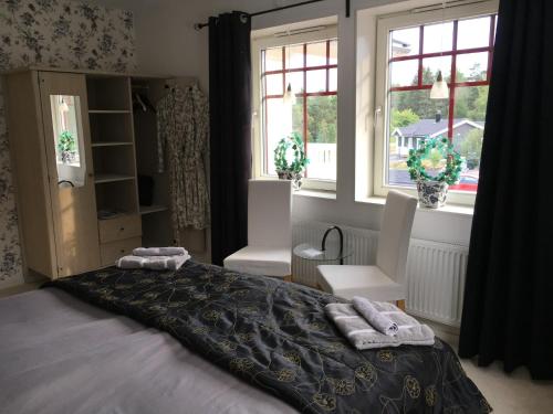a bedroom with a bed and two chairs and windows at Öregrund BnB in Öregrund