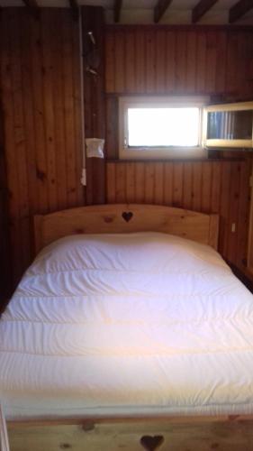 Una cama en una habitación de madera con ventana. en Le Valmandine, en La Bresse