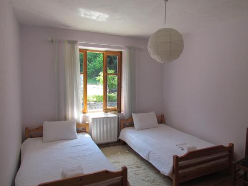 two beds in a room with a window at Hotel Germenji in Gërmenj