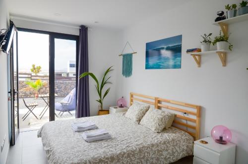 a white bedroom with a bed and a balcony at MAAR House Lajares in Lajares