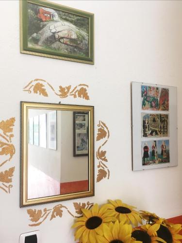 a mirror on a wall with flowers in front of it at Bed and Breakfast da Antonio - Orgosolo in Orgosolo