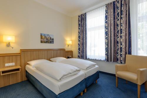 una habitación de hotel con 2 camas y una silla en Mercure Hotel Luebeck City Center, en Lübeck