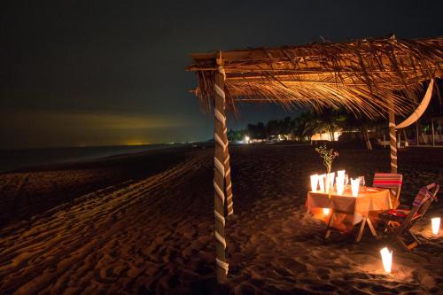 a table and chairs on a beach at night at Hotel Cafe del Sol in Monterrico