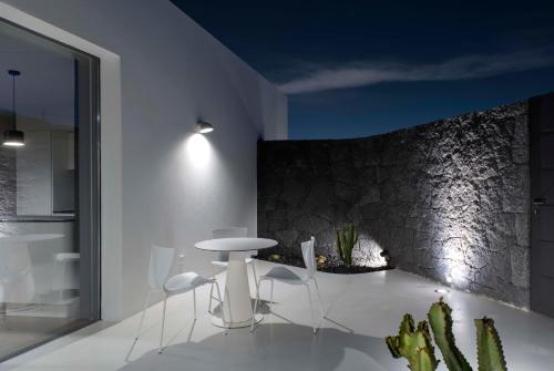 a dining room with white chairs and a stone wall at VULKANO LOFT in Mala