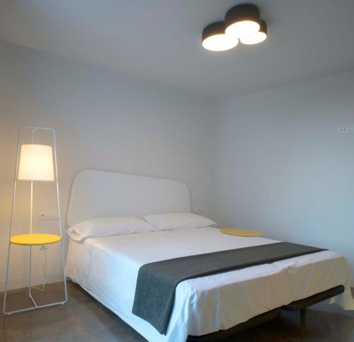 a bedroom with a white bed and a lamp at VULKANO LOFT in Mala