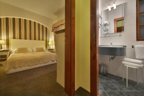 ein Bad mit einem Bett und einem Waschbecken in einem Zimmer in der Unterkunft Hotel U 3 Pstrosu in Prag