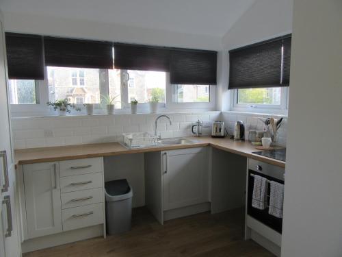 a kitchen with white cabinets and a sink and two windows at Central Living Apartment in Weston-super-Mare