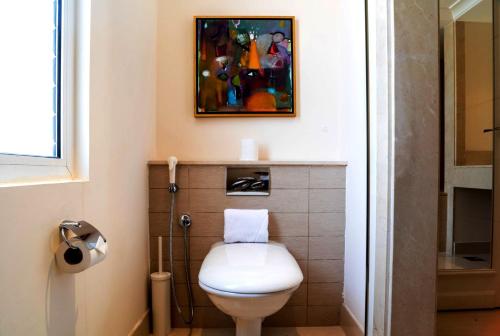 a bathroom with a toilet and a painting on the wall at Vivienda Hotel Villas in Riyadh