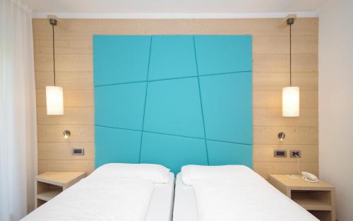 two beds in a room with a blue wall at Hotel Montana in Madonna di Campiglio