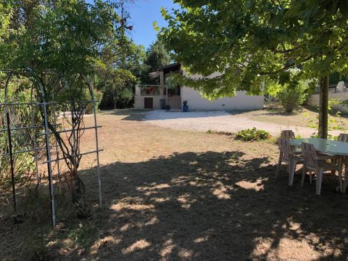 einen Tisch und Stühle unter einem Baum im Hof in der Unterkunft Maison d'en face in Salavas