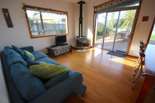a living room with a blue couch and a fireplace at BOB - Bach on the Beach in Pakawau