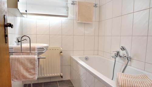 a white bathroom with a tub and a sink at Haus Sigge Ferienwohnungen in Bad Sassendorf
