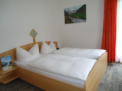 a bedroom with a bed with white sheets and pillows at Landhaus Kröll in Hippach