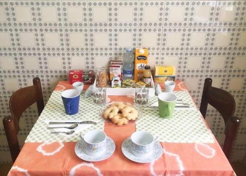 a table with cups and plates of food on it at Bed and Breakfast da Antonio - Orgosolo in Orgosolo