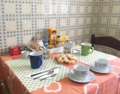 a table with cups and plates and donuts on it at Bed and Breakfast da Antonio - Orgosolo in Orgosolo