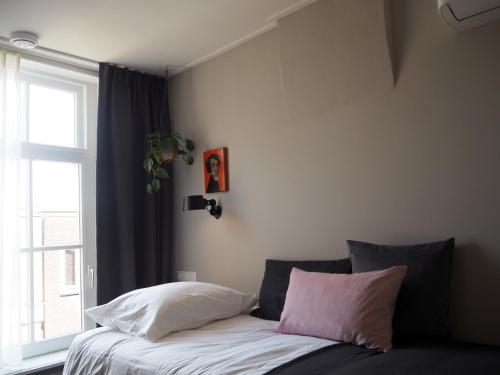 łóżko z 2 poduszkami i oknem w pokoju w obiekcie Lino City Hotel w mieście Nijmegen