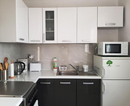 a kitchen with white cabinets and a sink and a microwave at Apartament MARGARITA in Kielce