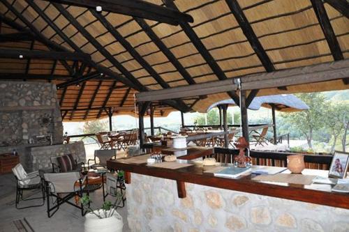 an outdoor restaurant with a bar and tables and chairs at Kapika Waterfall Lodge in Epupa