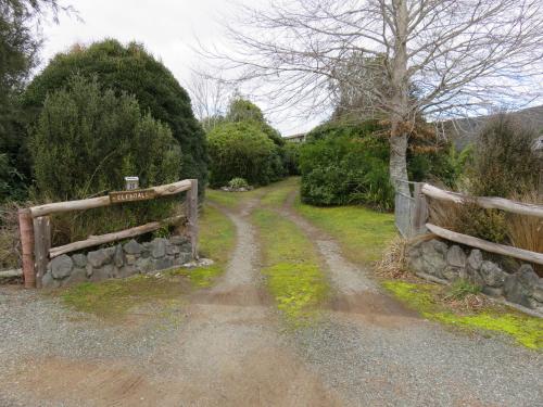 a dirt road next to a stone fence at Glendale River View in Manapouri