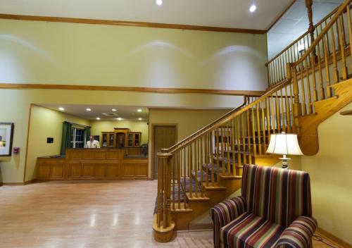 a living room with a staircase with a chair and a lamp at Country Inn & Suites by Radisson, Rock Falls, IL in Rock Falls
