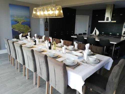 a long dining table with chairs and a white table cloth at Ocean View,Kinsale, Hosted by Exquisite holiday homes, sleeps 22 in Kinsale